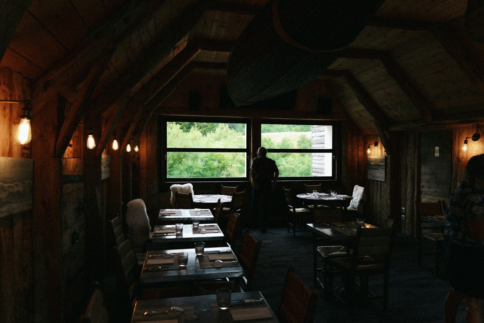A small restaurant dining room with large windows, set for the evening