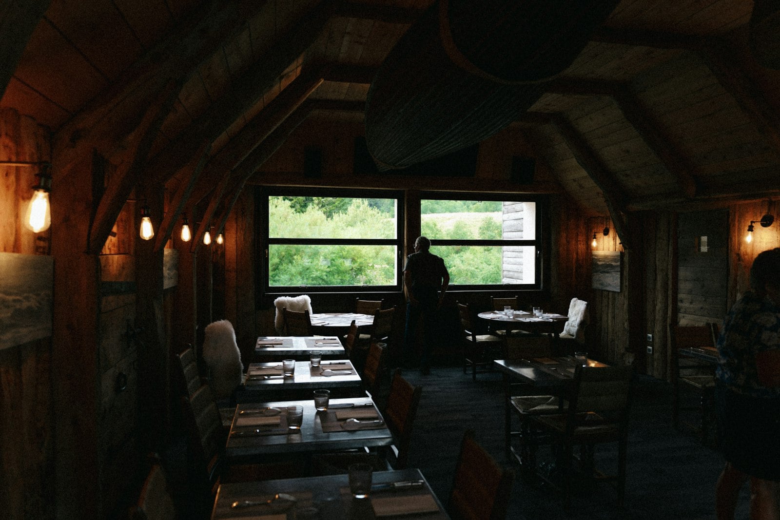 A small restaurant dining room with large windows, set for the evening
