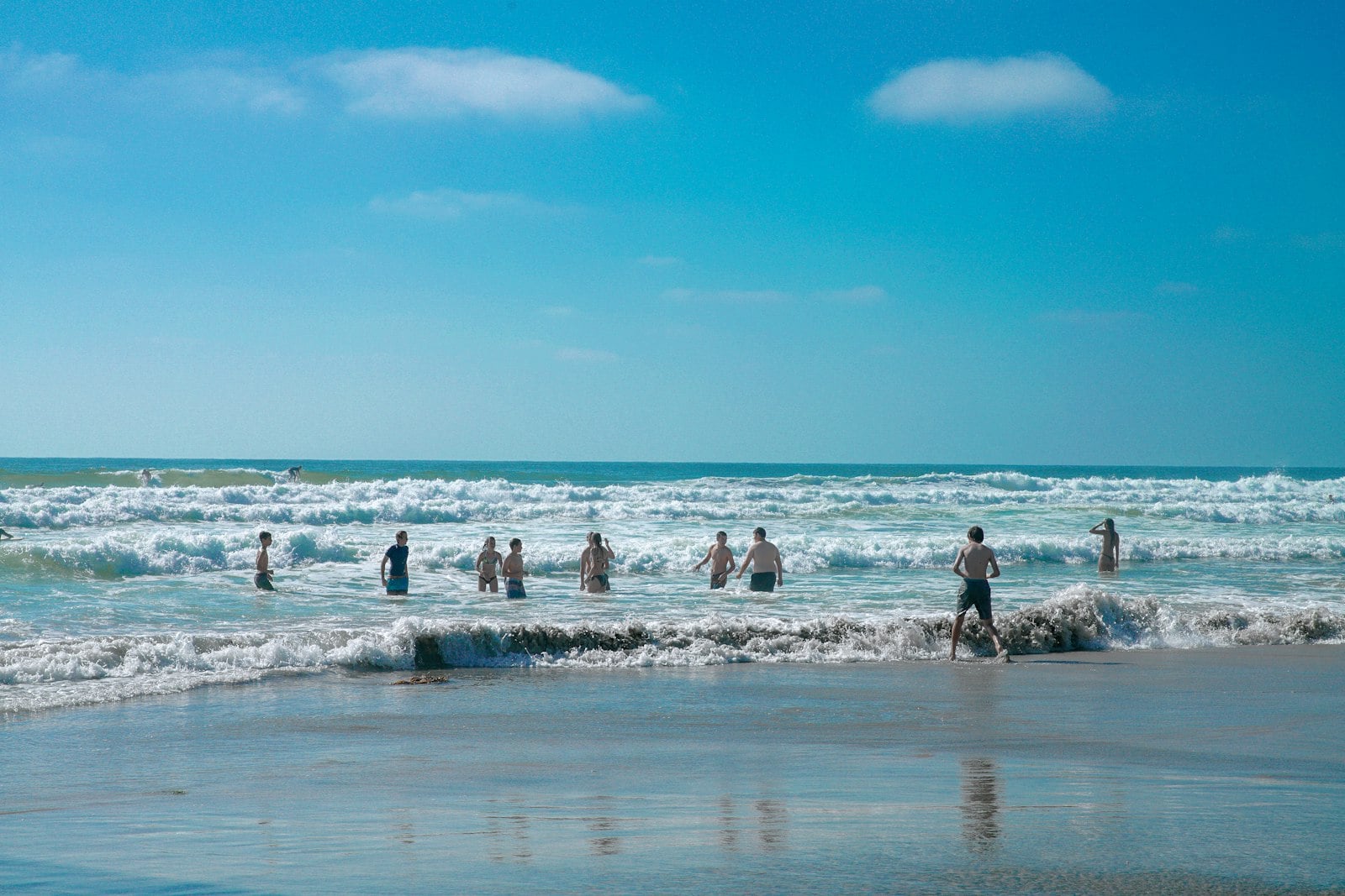 Families spread across a broad San Diego beach beside the Pacific Ocean