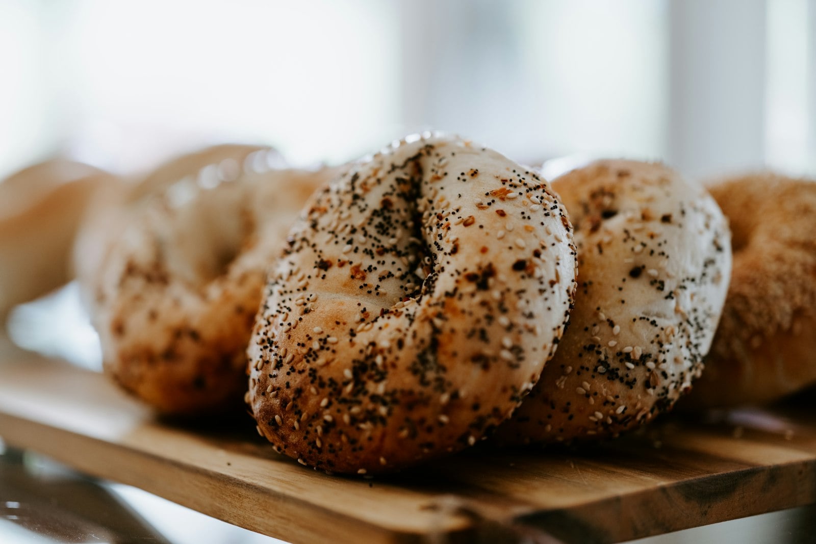 Fresh seeded bagels arranged together on a wooden bakery board