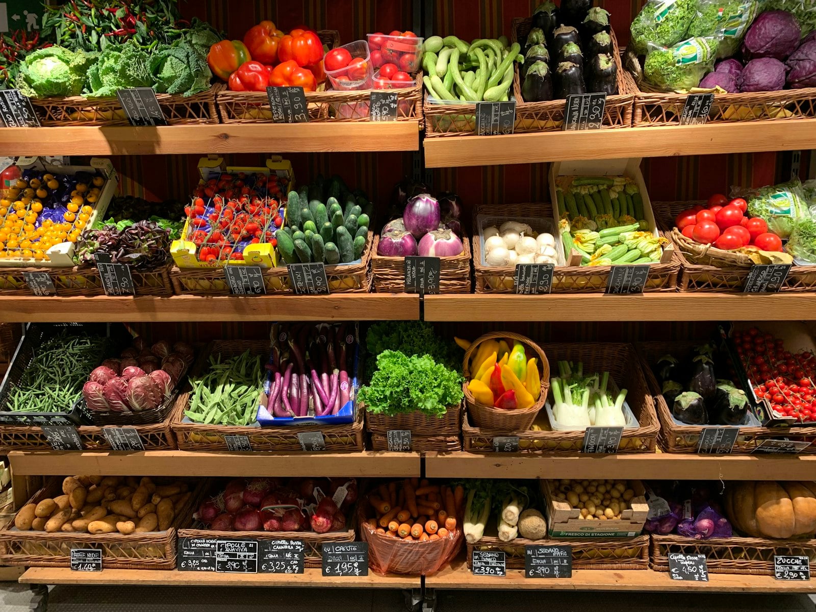 Colorful vegetables arranged across wooden market shelves