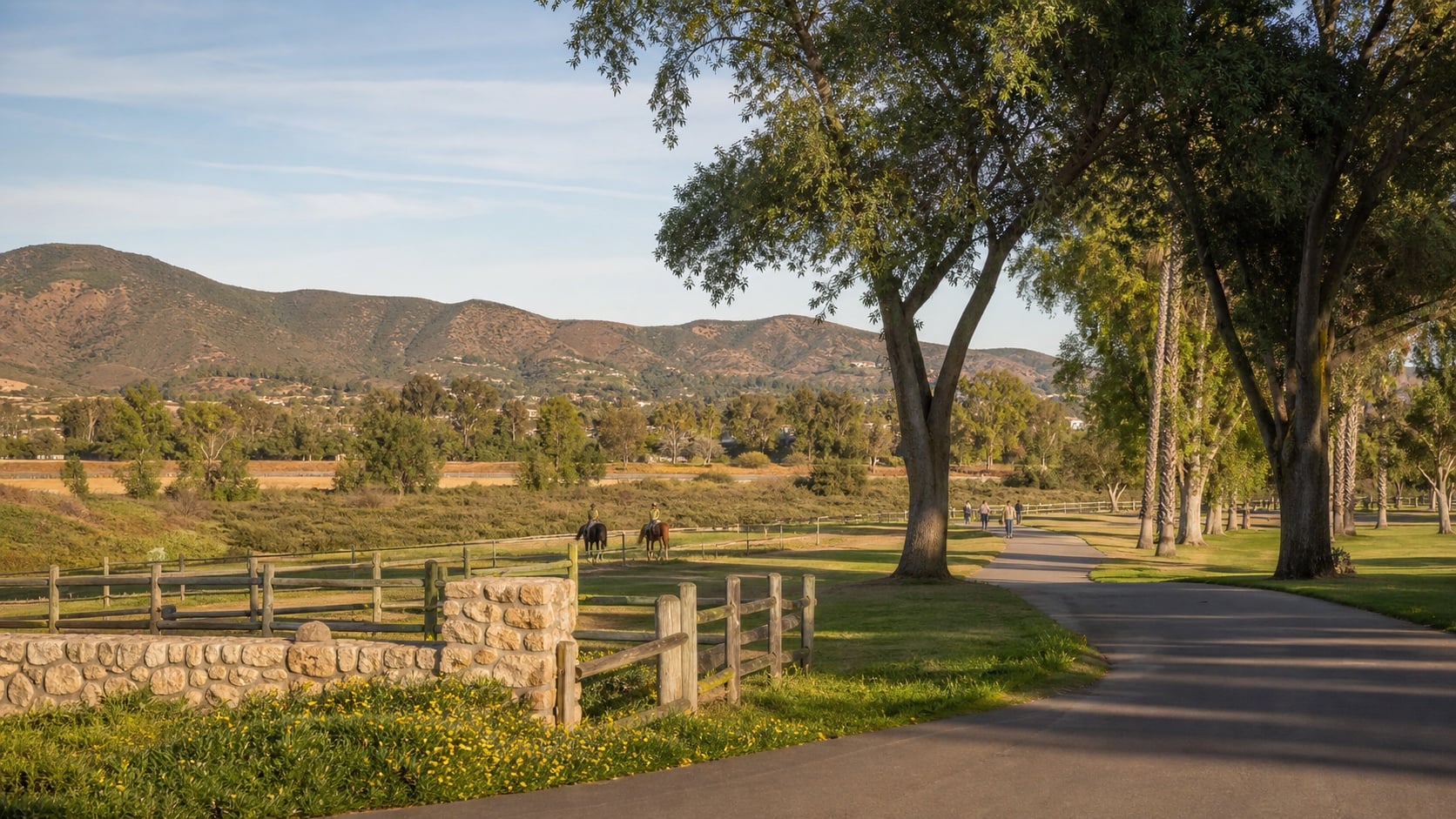 A tree-lined path, riders on horseback, and open foothills in Bonita