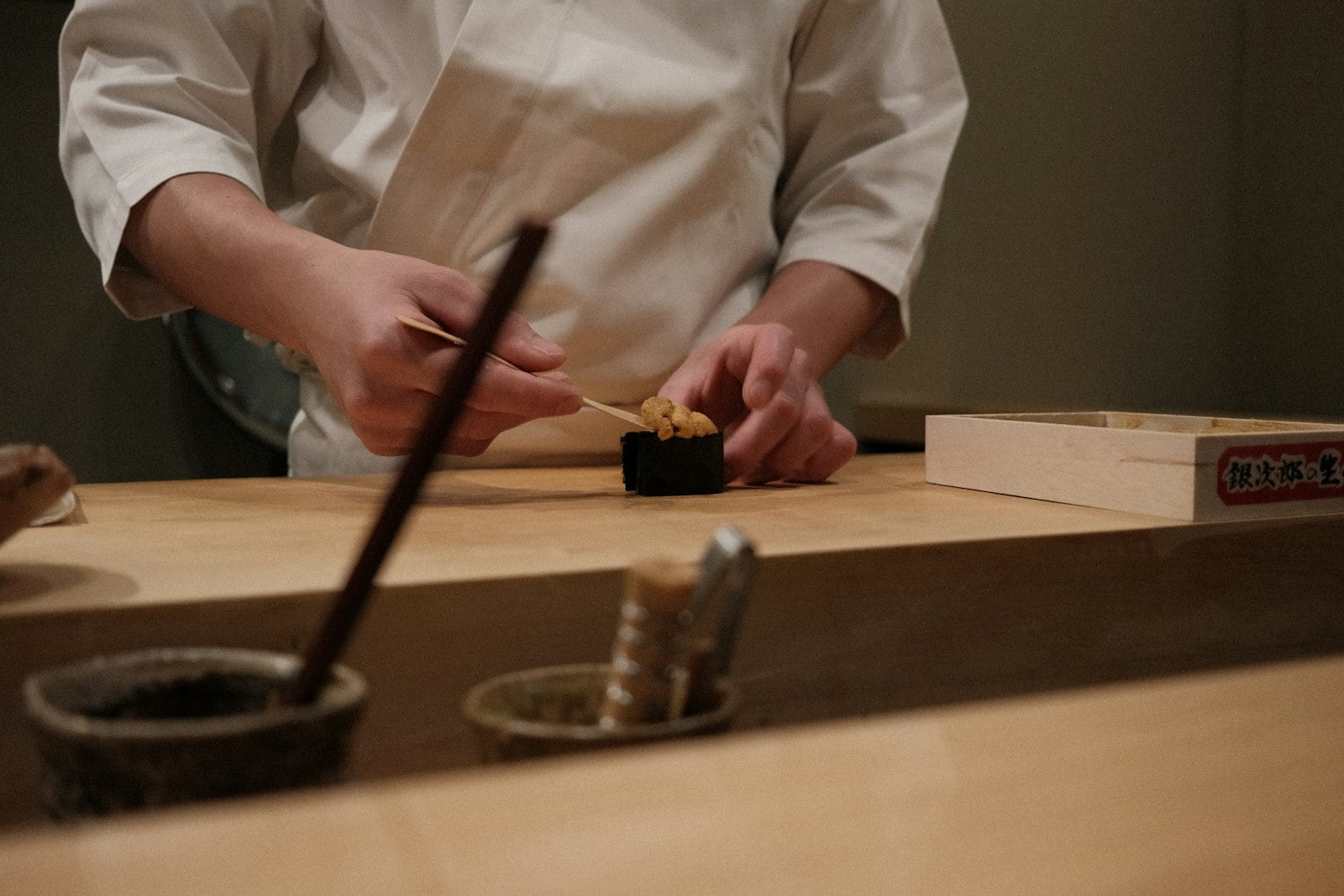 A chef preparing sushi on a wooden counter