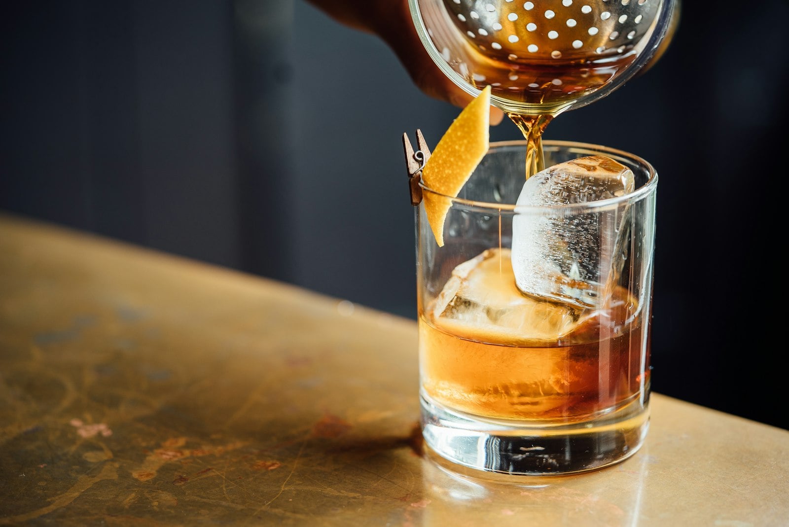 A bartender pouring a measured spirit behind a dim bar