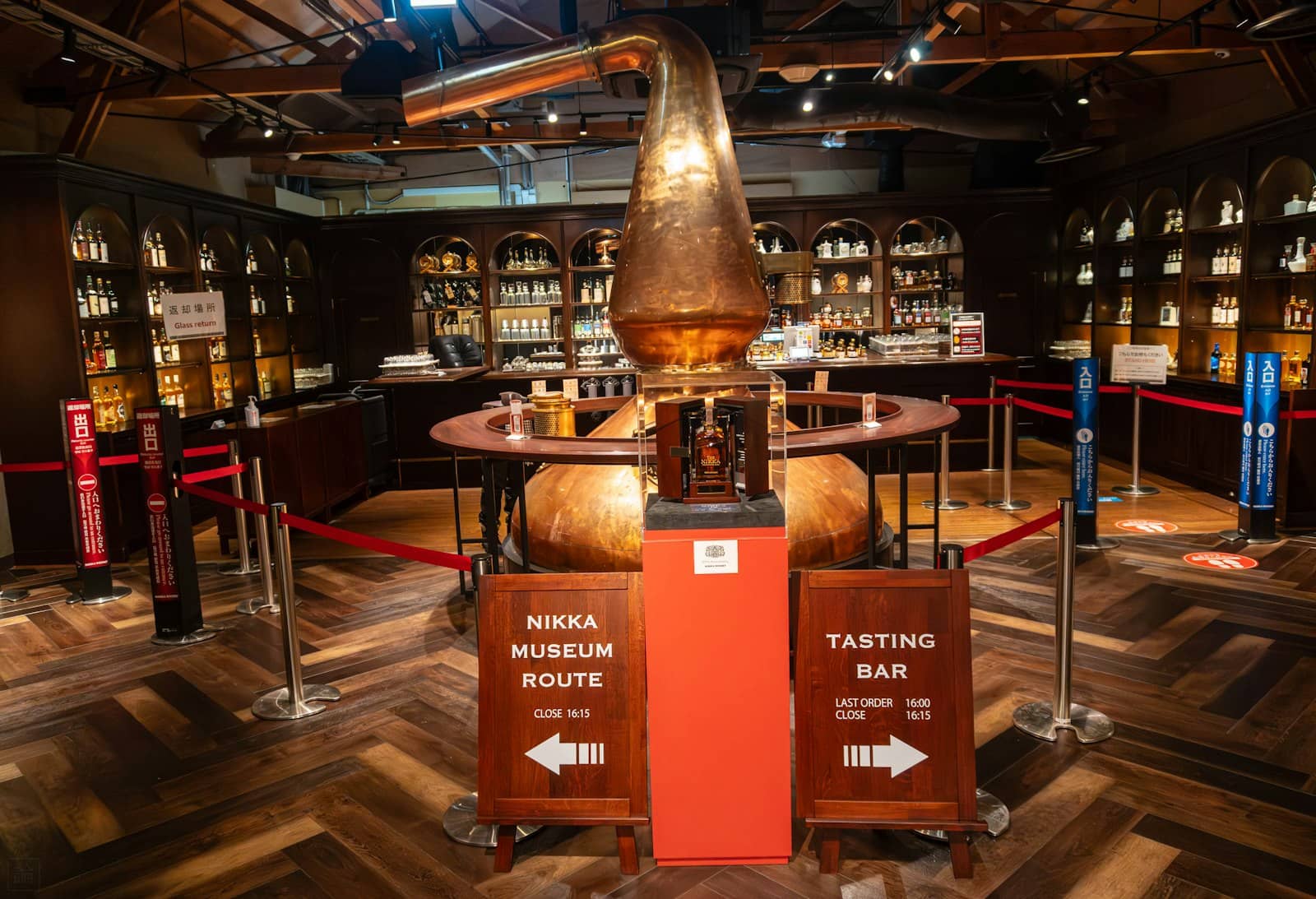A copper still and bottles behind a distillery tasting-room bar