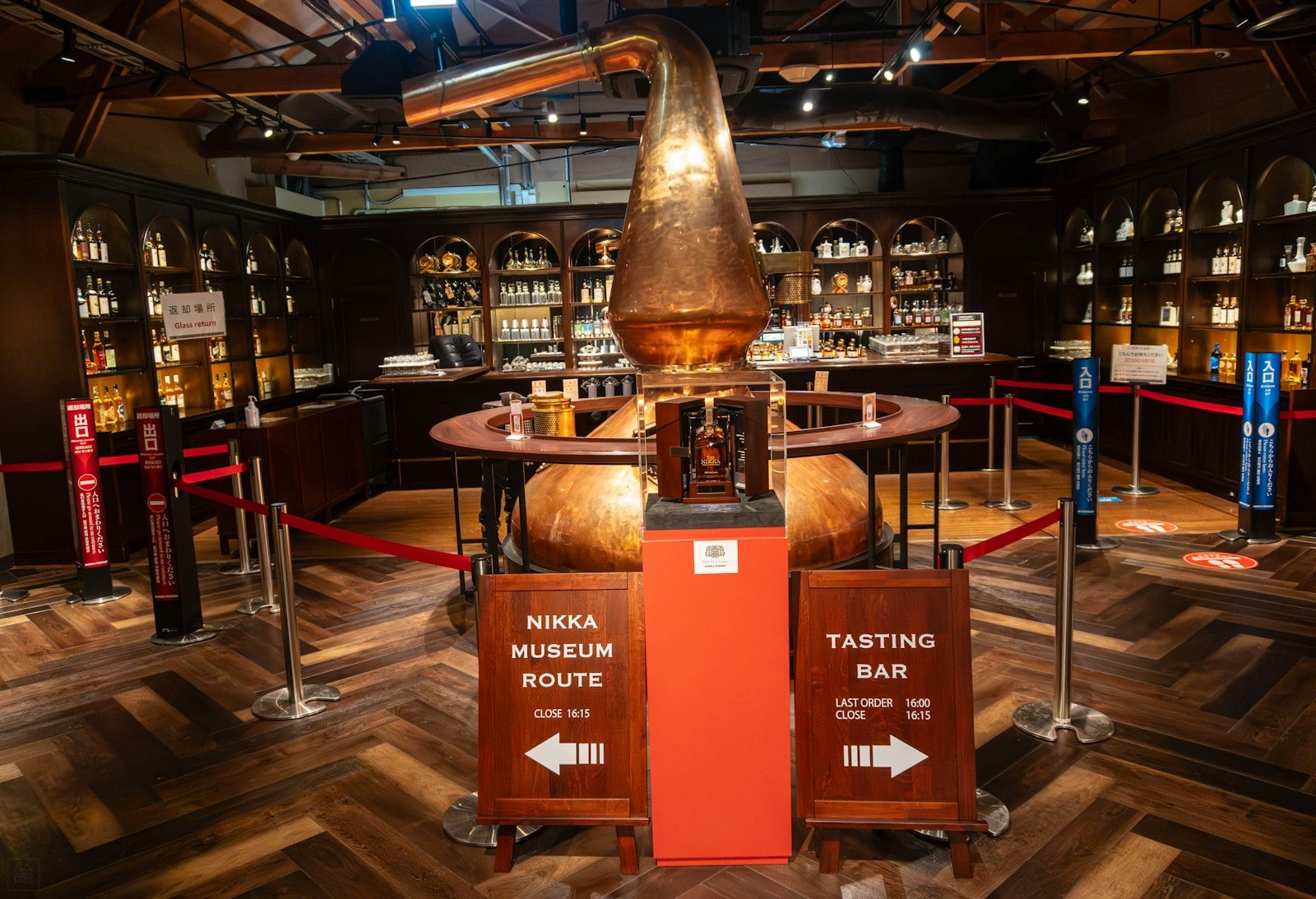 A copper still and bottles behind a distillery tasting-room bar