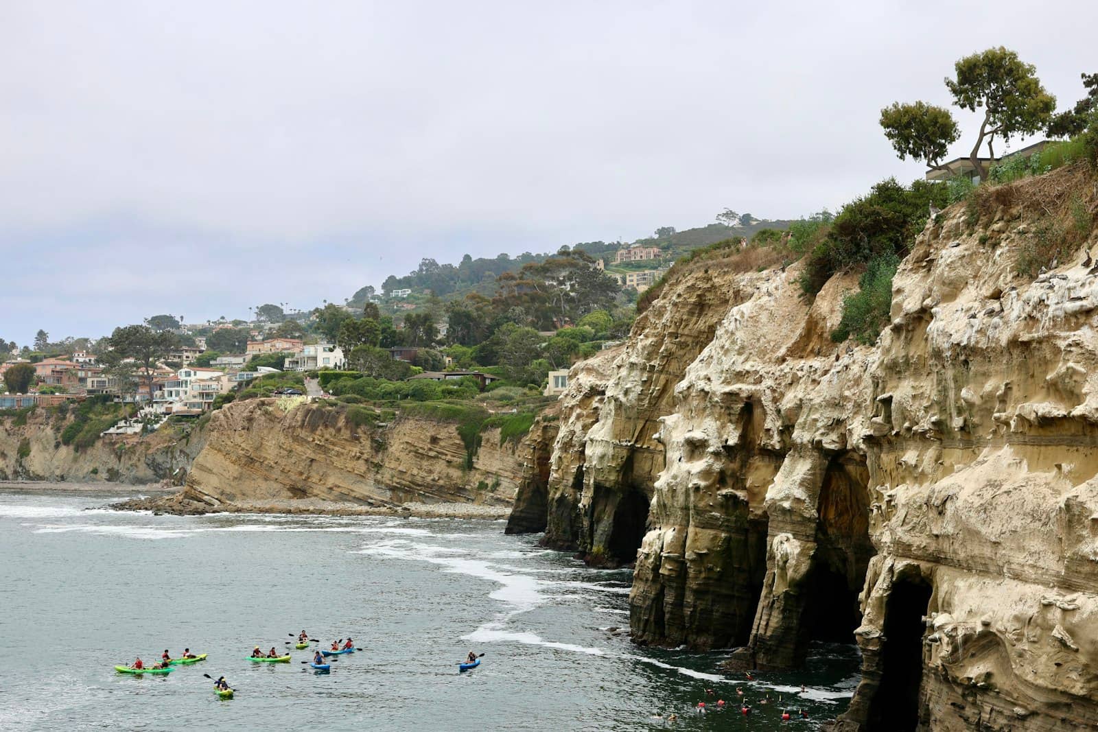 Guided kayakers paddling beside coastal cliffs
