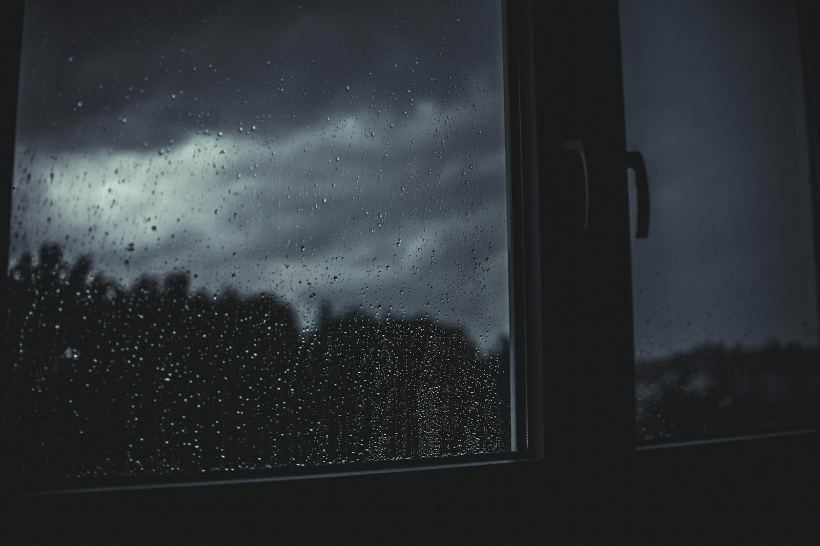 Rain running down a window with a warm indoor San Diego room beyond the glass