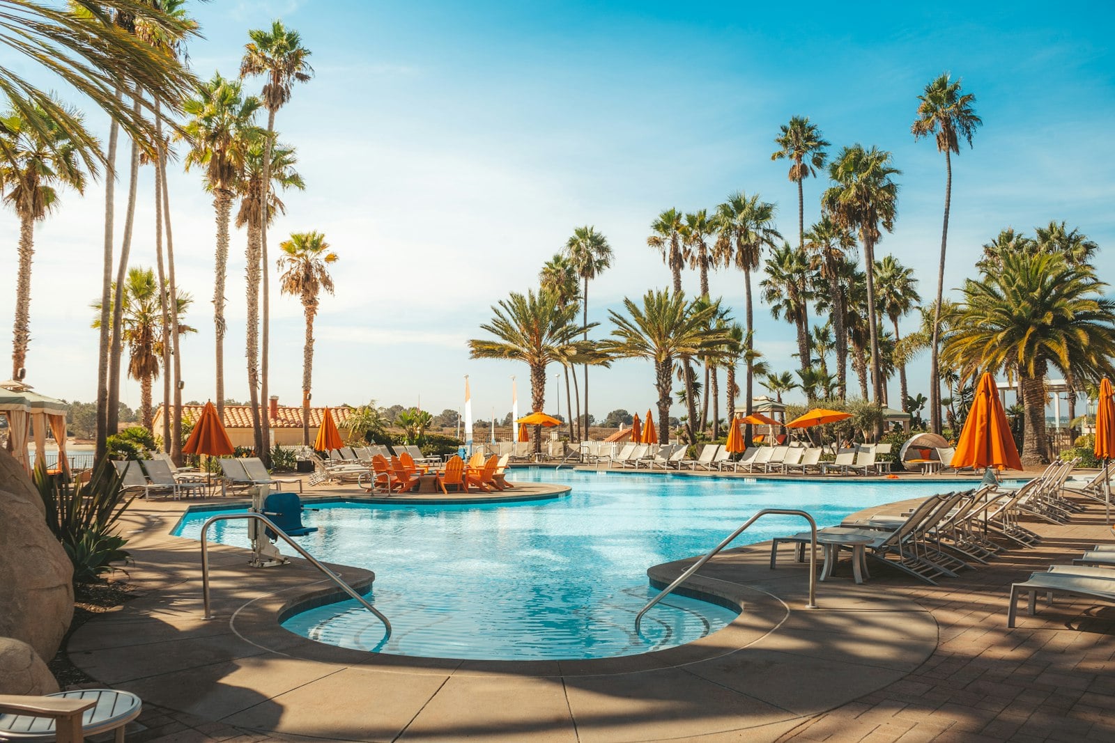 A resort swimming pool ringed by palm trees under a clear Southern California sky