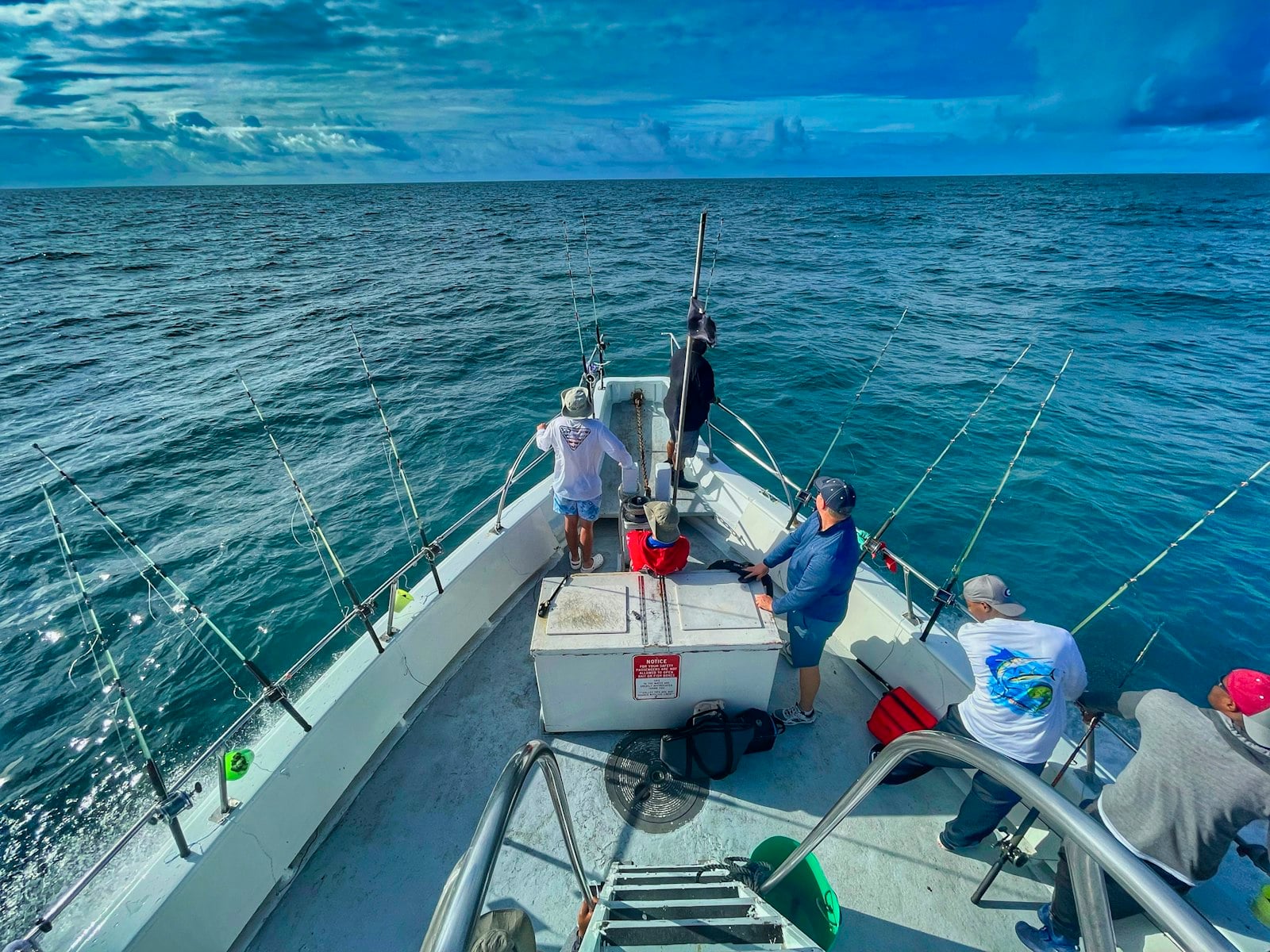 People on the deck of a white boat under way on open water