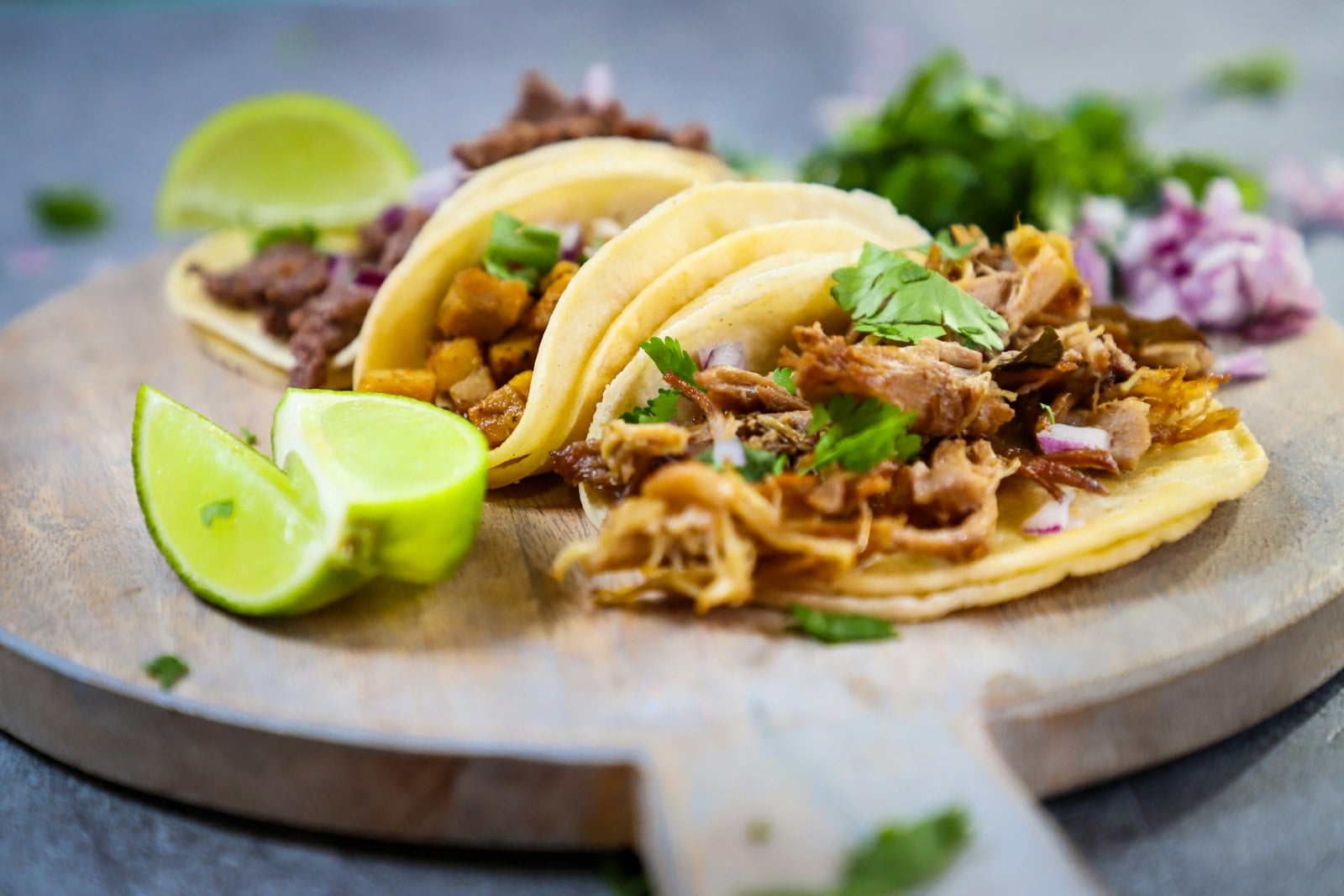 Street tacos with lime and cilantro on a wooden board