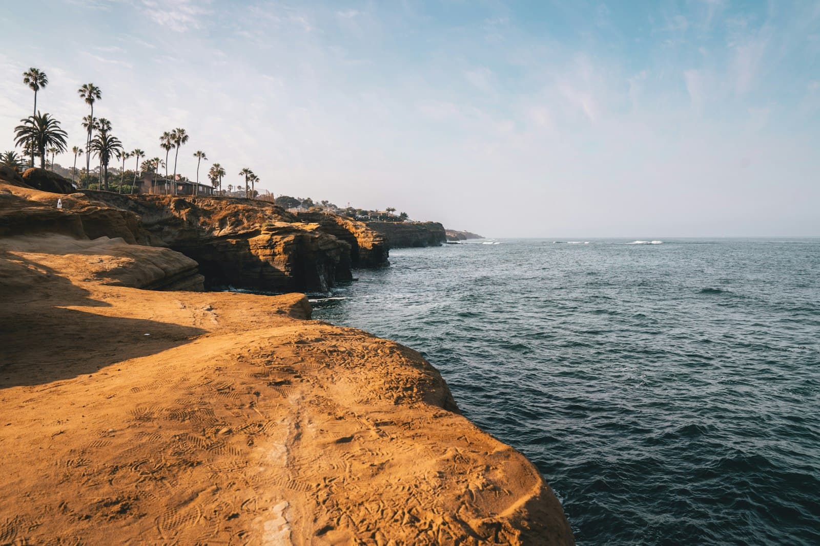 People on rock formations above the water on the San Diego coast