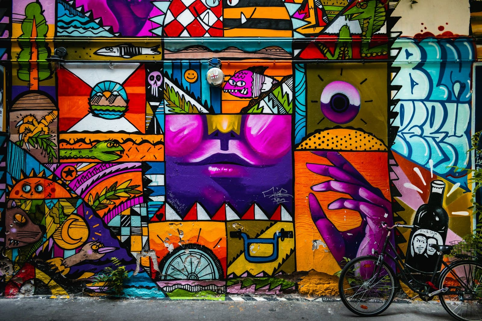 A wall covered end to end in a bold, cartoonish mural, a bicycle leaning against it