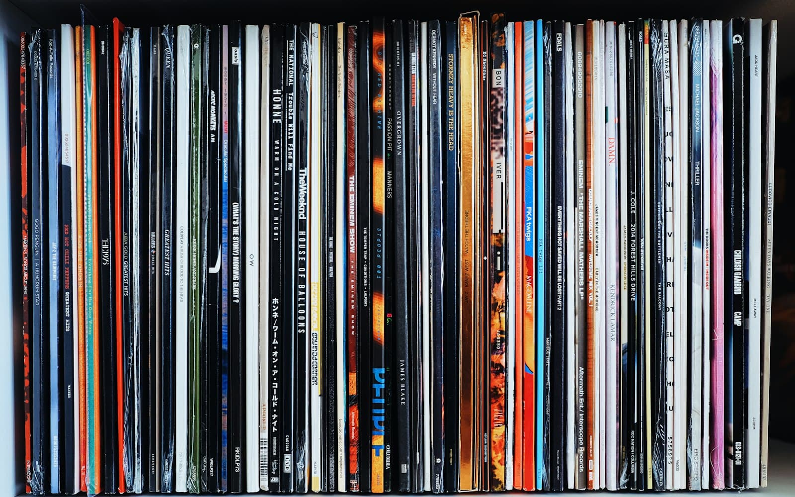 A packed shelf of vinyl records seen edge-on, spines in every colour